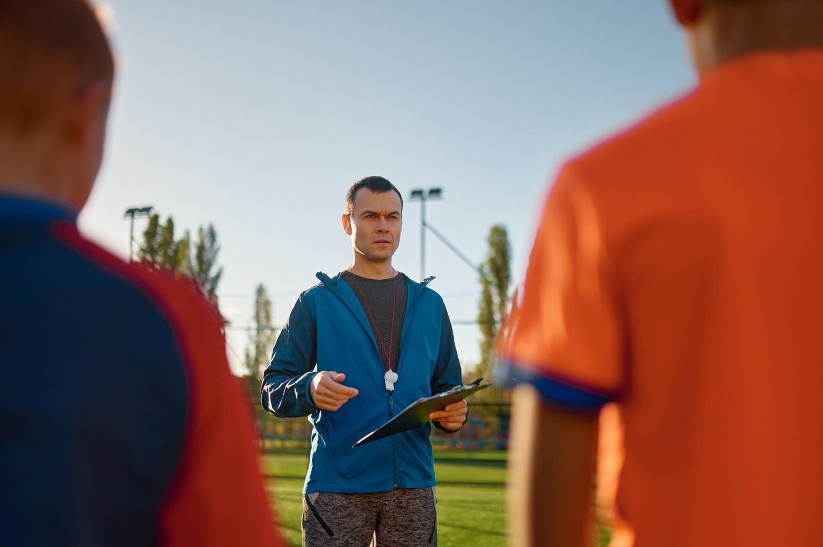 Young football coach talking to a group of young players