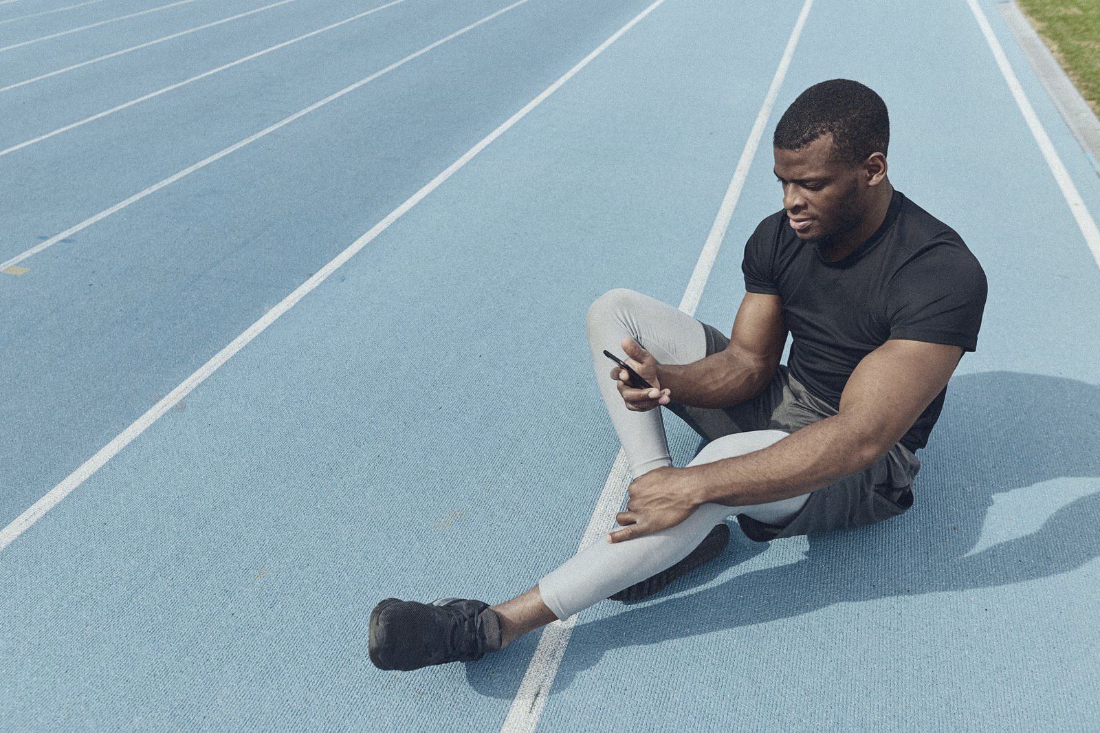 Athlete on a running track checking their phone